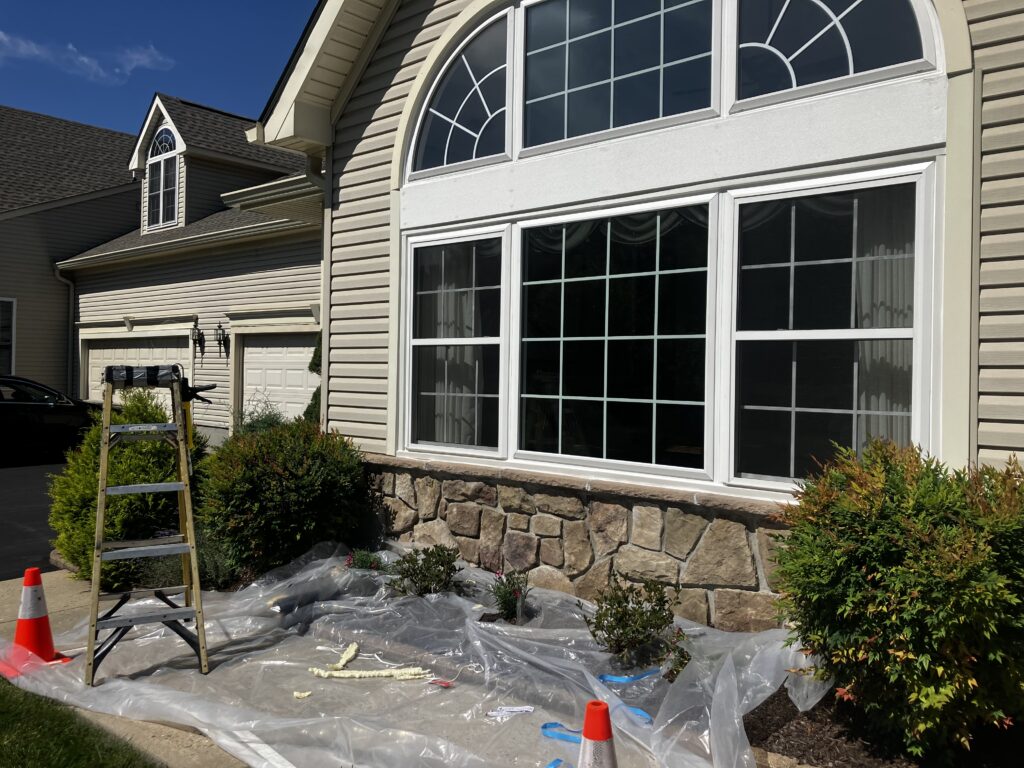Ladder and construction materials near a newly installed energy-efficient window on a residential home, showcasing Azinex Construction's window replacement services.