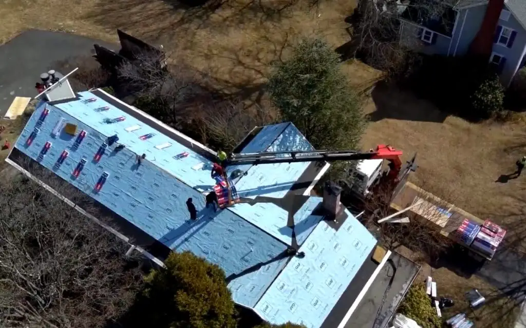 Roof replacement in progress with workers and equipment on a residential structure, showcasing high-quality roofing materials and installation techniques by Azinex Construction.